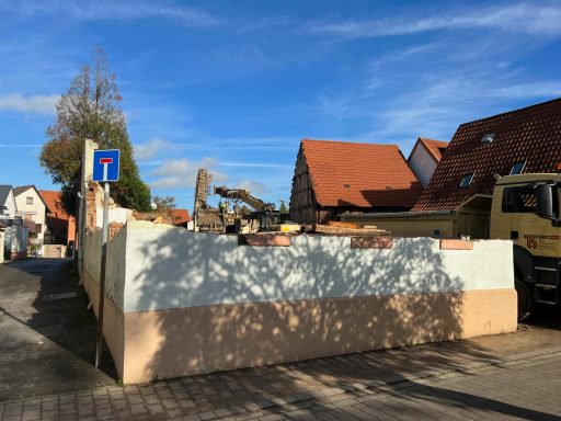 Blick auf eine Baustelle mit einem Lkw und einem Schattenwurf auf die Wand.