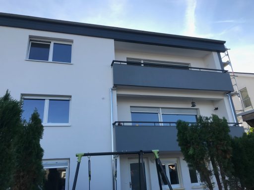 Moderne Wohnhausfassade mit Balkonen und Schaukel im Vordergrund.