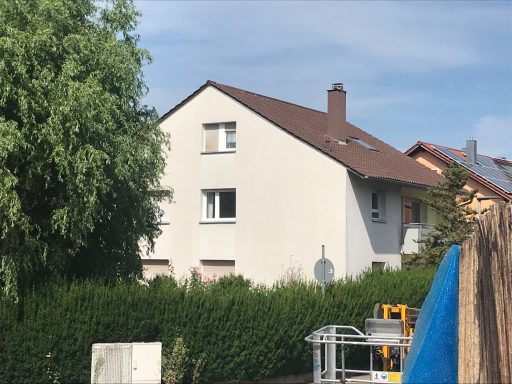 Ein zweigeschossiges Wohnhaus mit heller Fassade und grünem Garten.